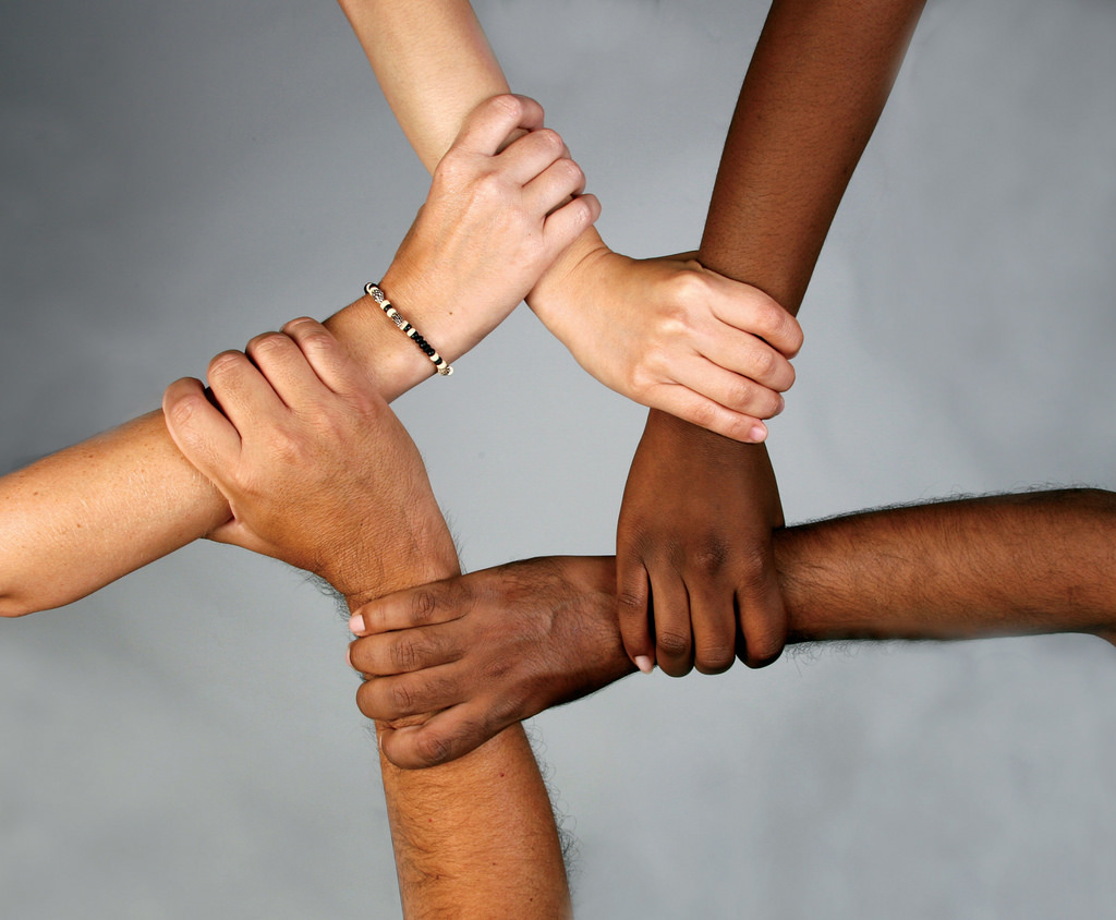Five forearms and hands of varying skin tones interlocked
