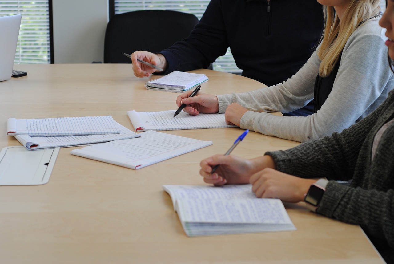 Three people collaborating at a conference table with notepads in front of them