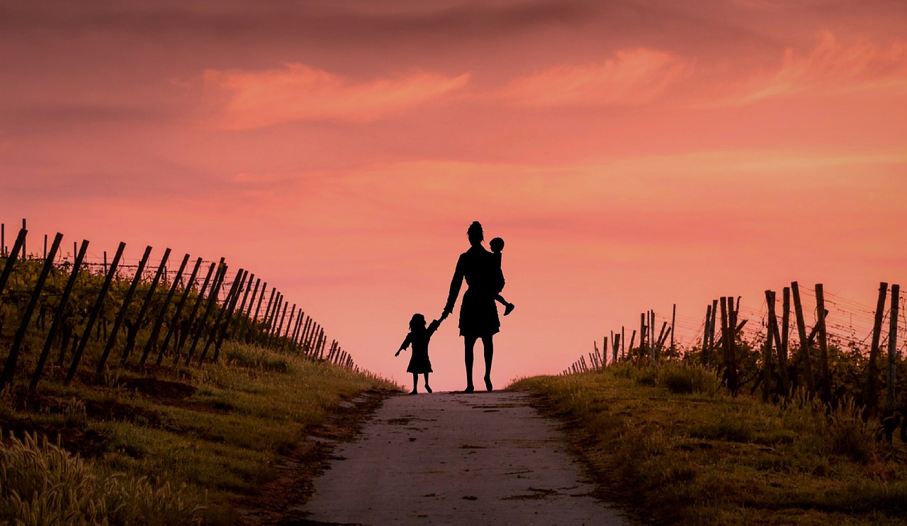 Women and two children backlit against a sunset and walking along a path