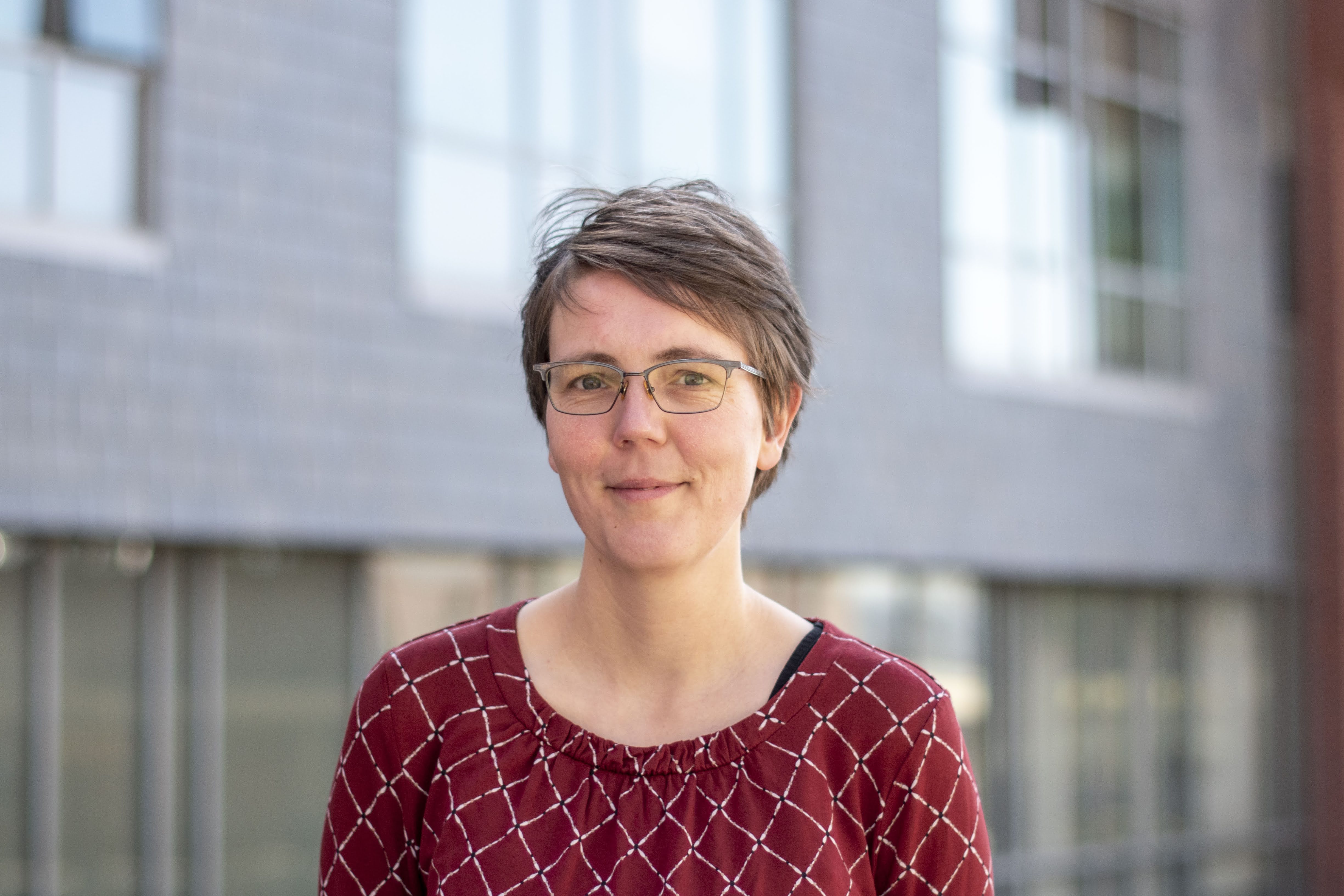 Julia Jorati standing outside in front of a building with large windows.
