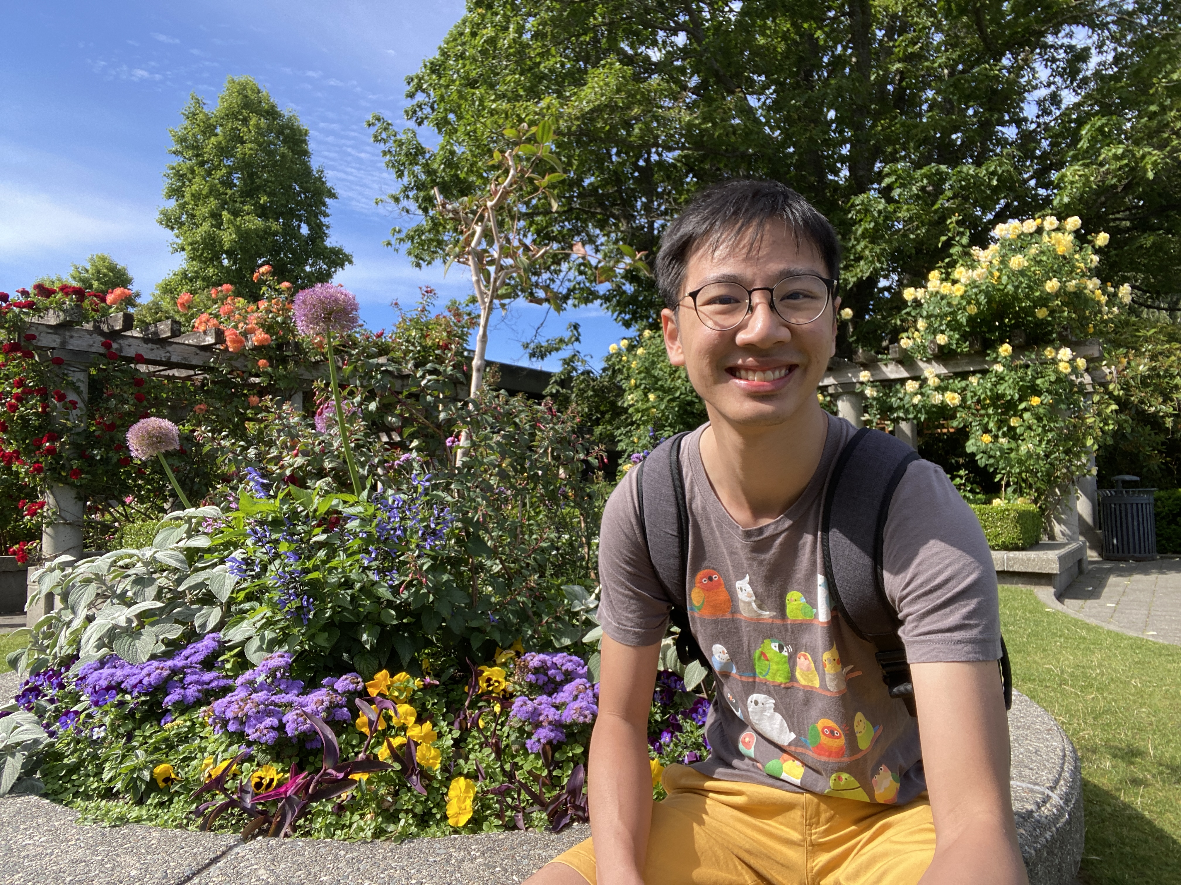A picture of Frederick smiling in front of flowers