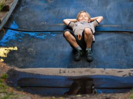 A child laying down with their hands behind their head smiling